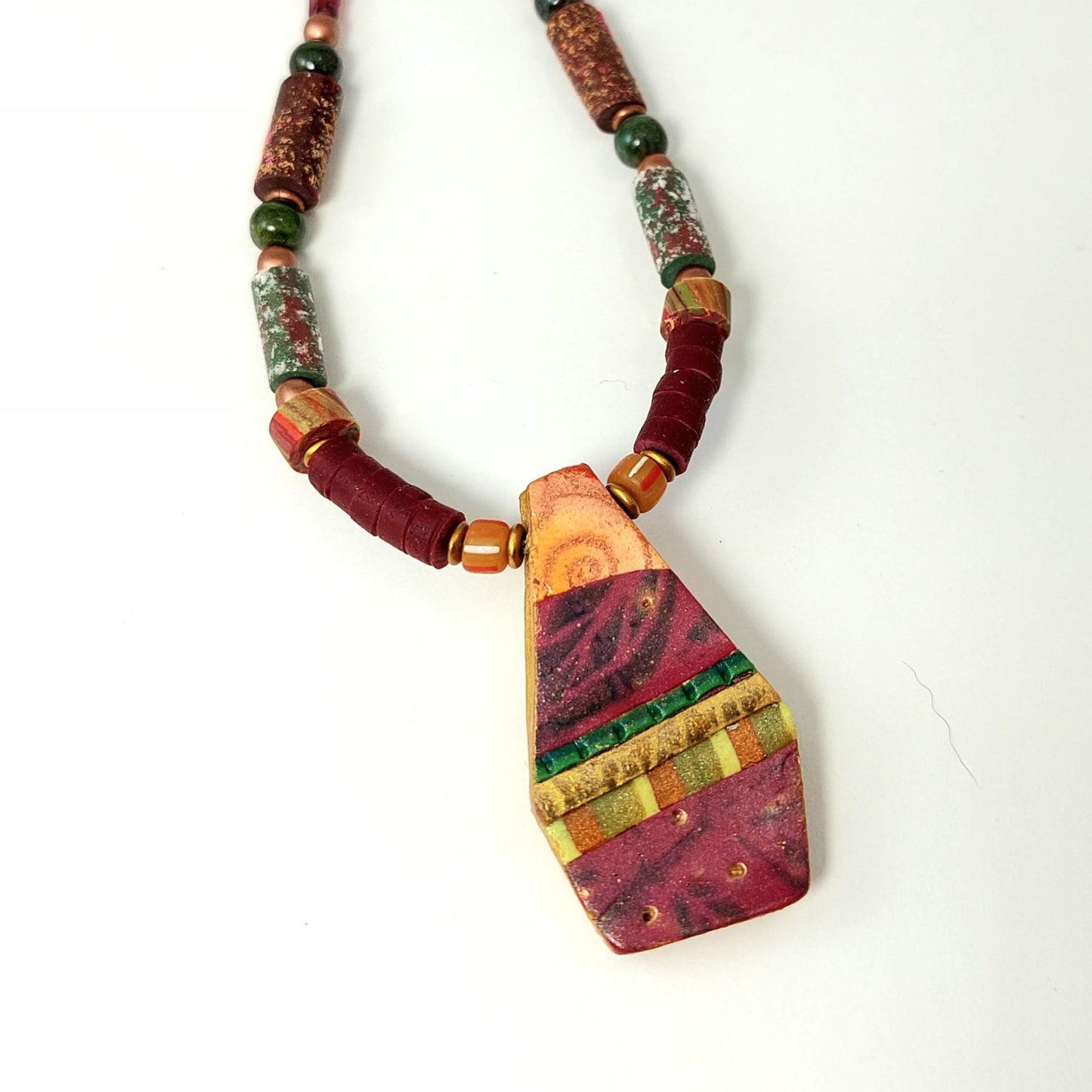 Close-up view of Geometric Collage Pendant Necklace. Detailed with swirls, subtle leaf designs, geometric patterns, and gold leaf.  Very lightweight and comfortable to wear.  Pendant is 1.5 inches long and 1 inch wide. Free shipping in the US.