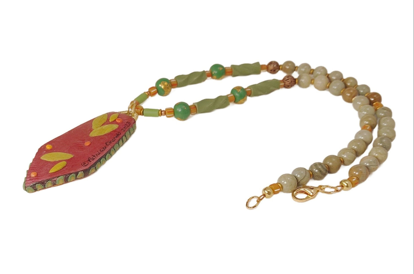 Back of beaded necklace with a red pendant on a white background