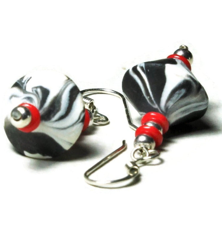 Closeup of polymer clay bicone earrings with sterling silver ear wires on white background