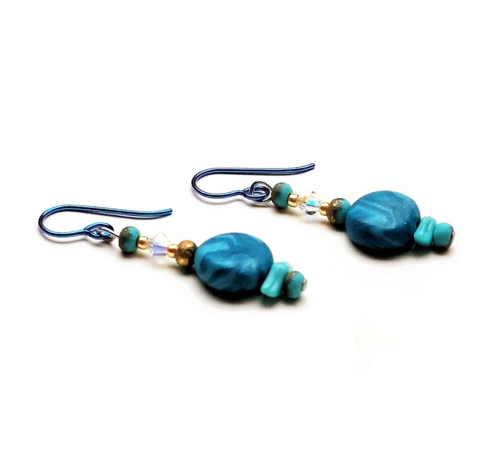 Polymer clay disk bead drop earrings with teal niobium ear wires on white background