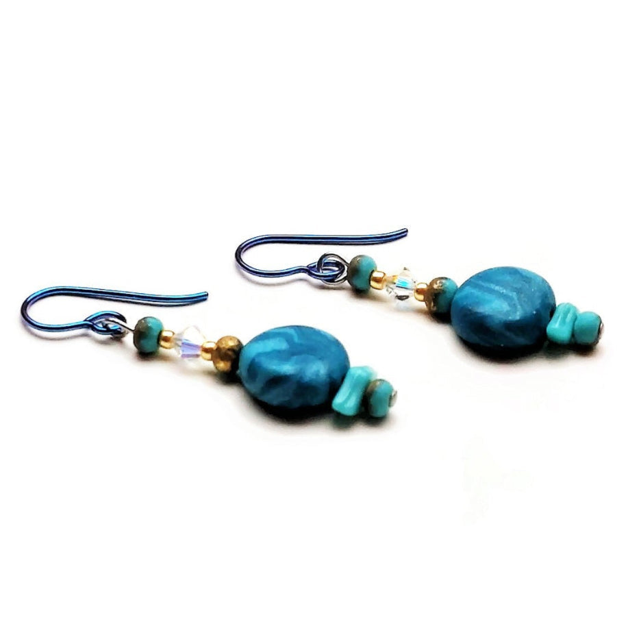 Polymer clay disk bead drop earrings with teal niobium ear wires on white background