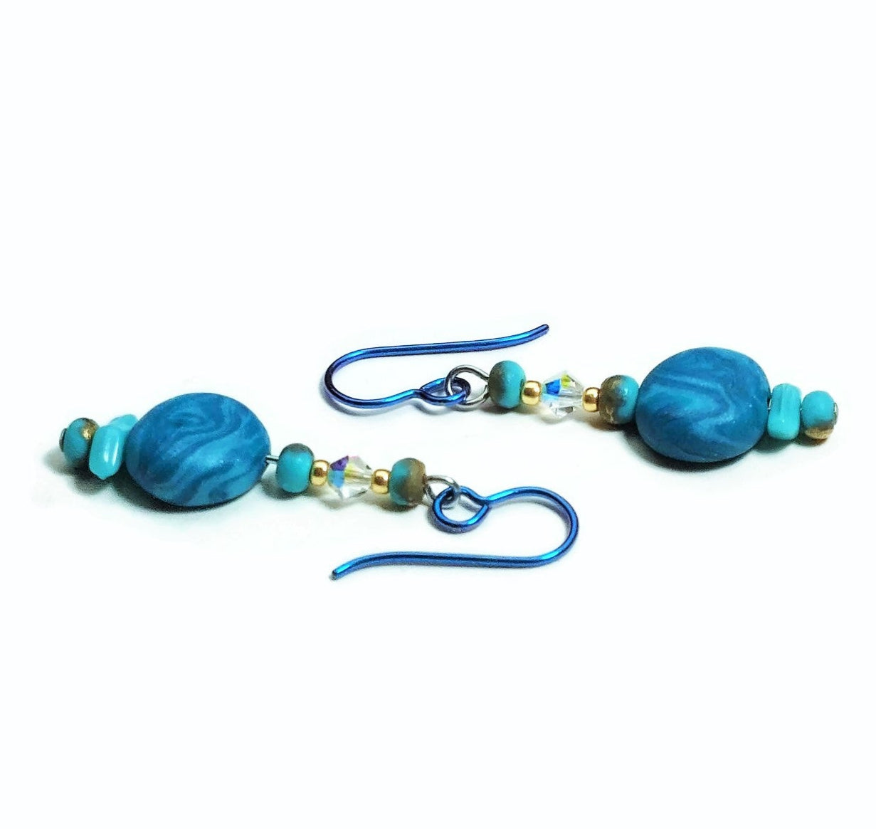 Polymer clay disk bead drop earrings with teal niobium ear wires on white background