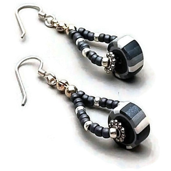 Closeup of polymer clay striped disk bead drop earrings with sterling silver ear wires on white background