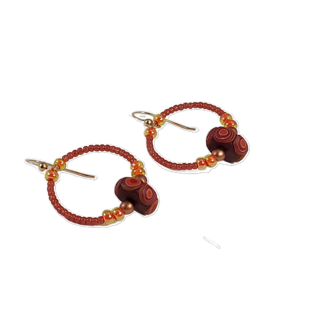 Pair of beaded earrings with terracotta and copper beads on a white background