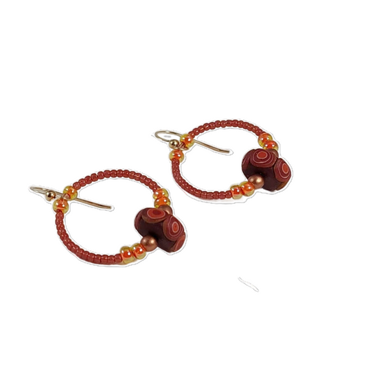 Pair of beaded earrings with terracotta and copper beads on a white background