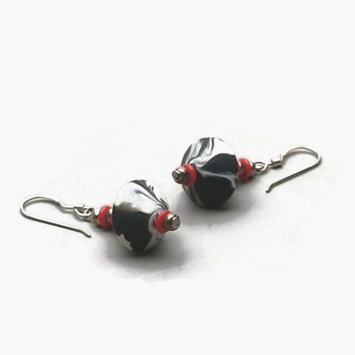 Pair of marbled black and white bicone earrings with red bead accents and sterling silver ear wires.
