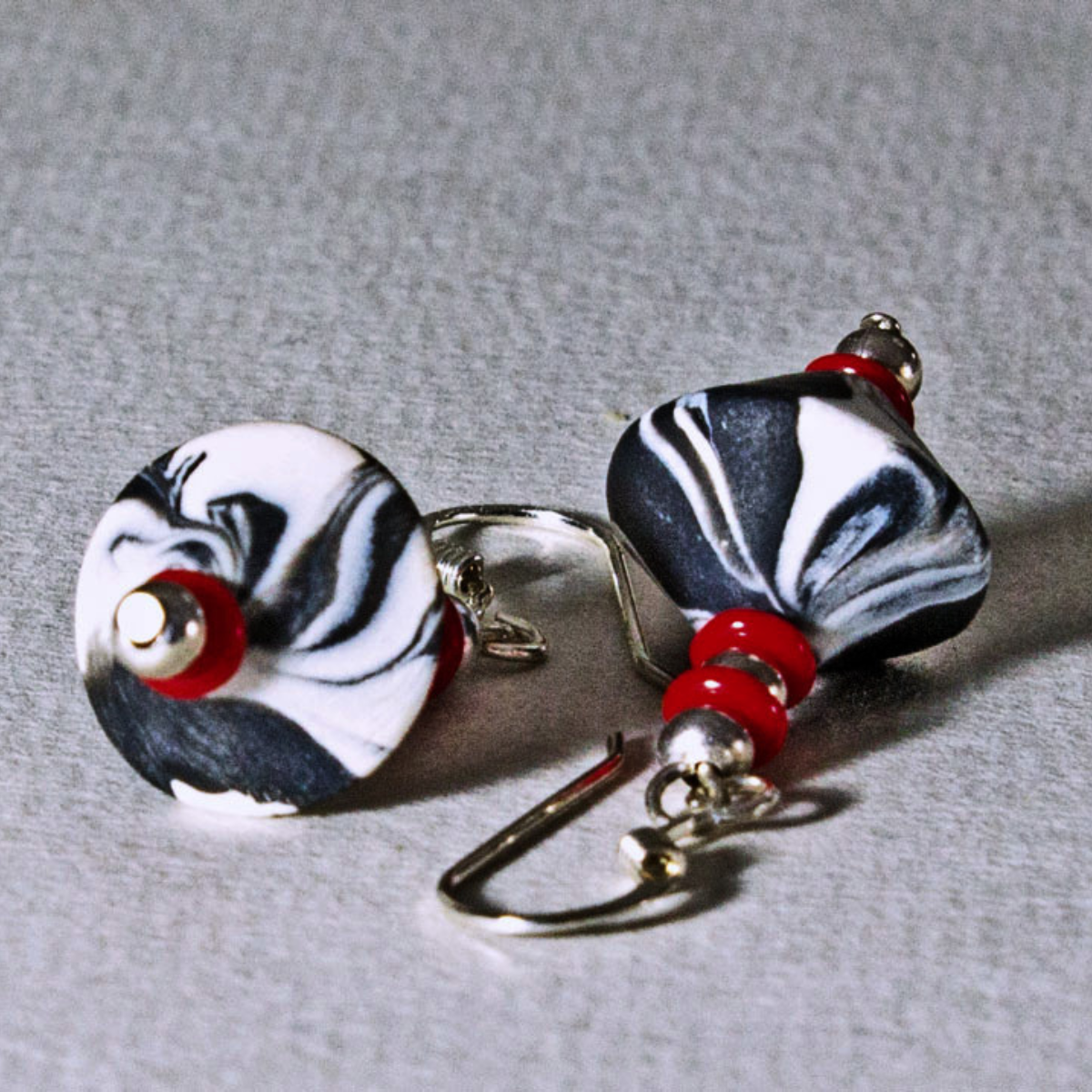 Pair of marbled black and white bicone earrings with red bead accents and sterling silver ear wires.