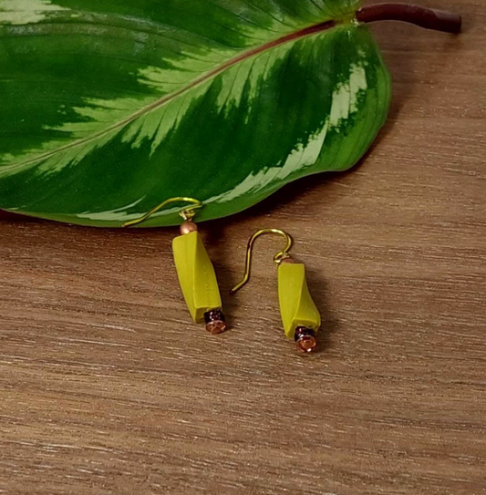Chartreuse earrings with gold hooks on a wooden surface with a green leaf