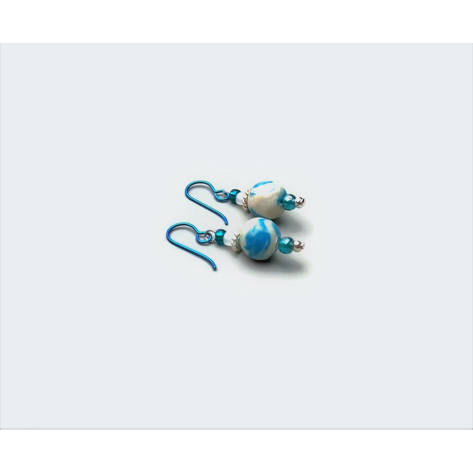 Polymer clay marbled drop earrings with teal niobium ear wires on white background