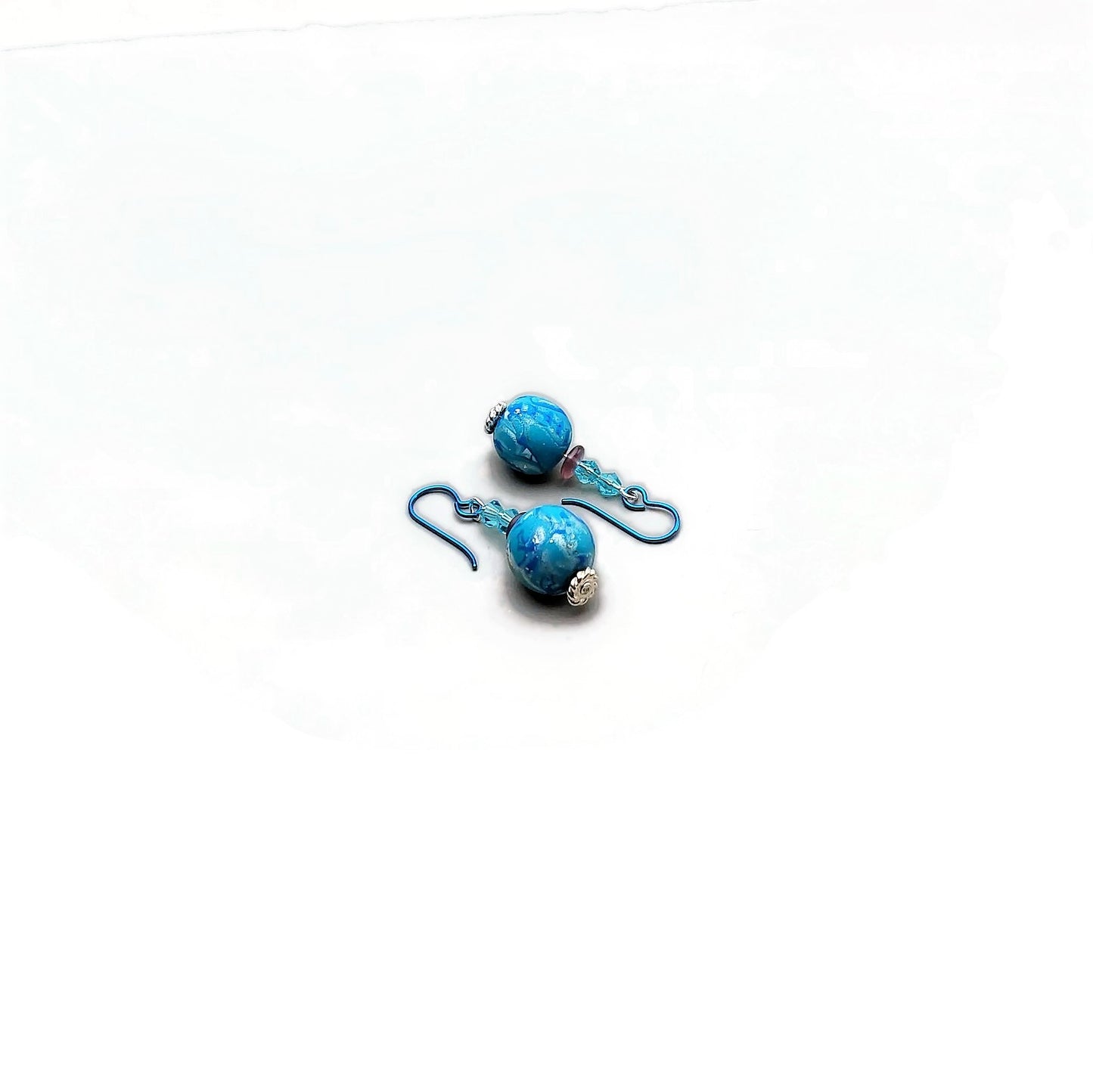 Polymer clay bead and crystal drop earrings with teal niobium ear wires on white background
