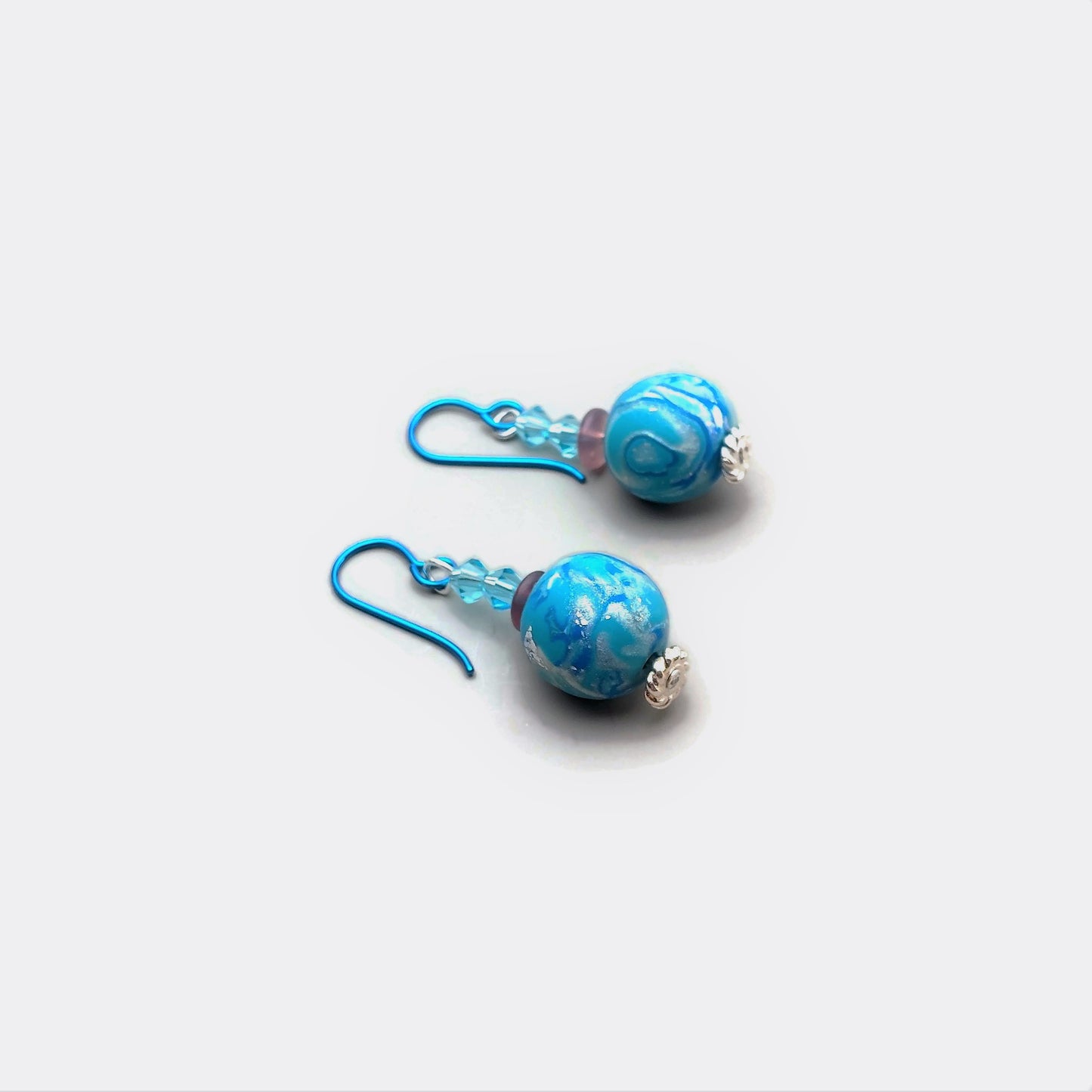 Polymer clay bead and crystal drop earrings with teal niobium ear wires on white background