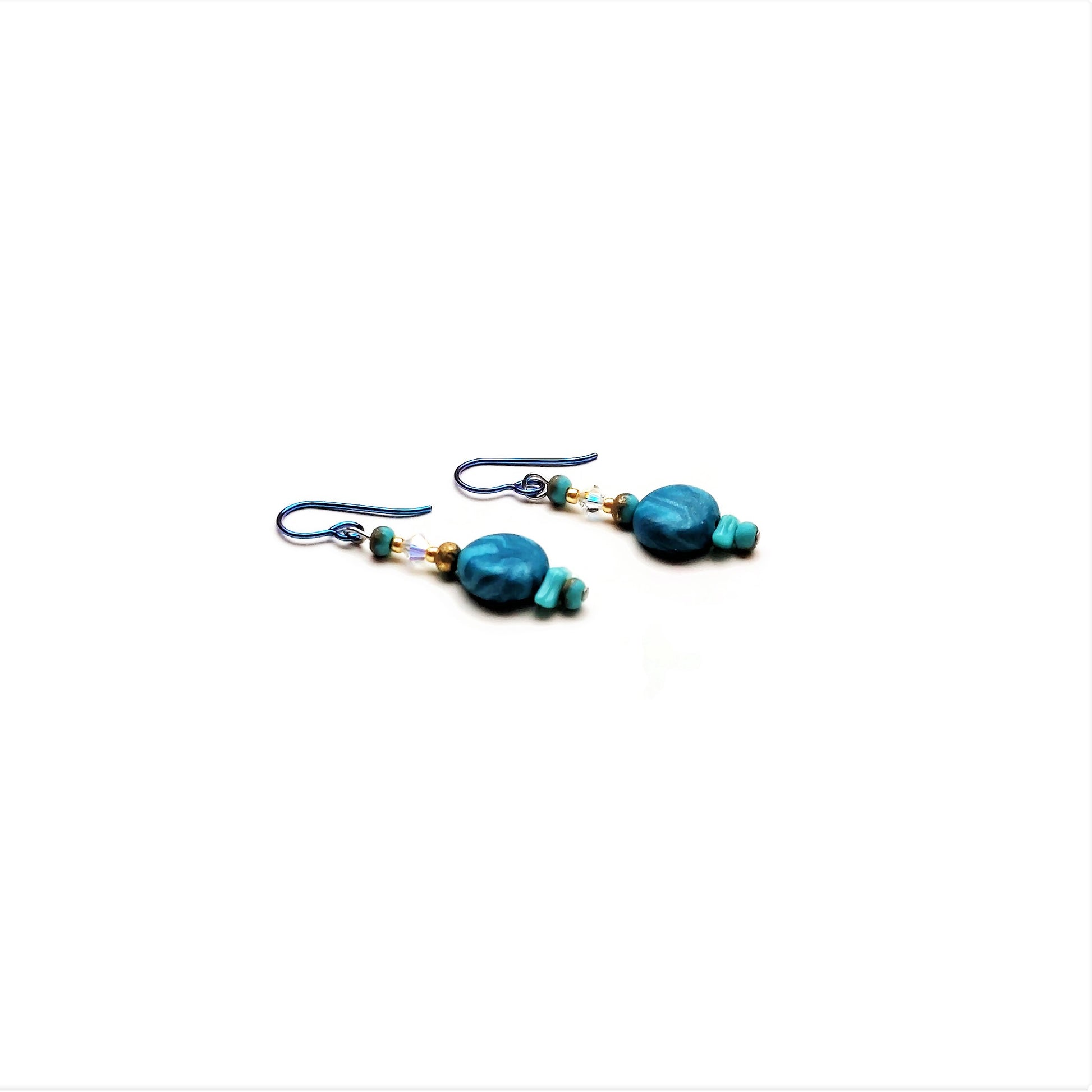 Polymer clay disk bead drop earrings with teal niobium ear wires on white background