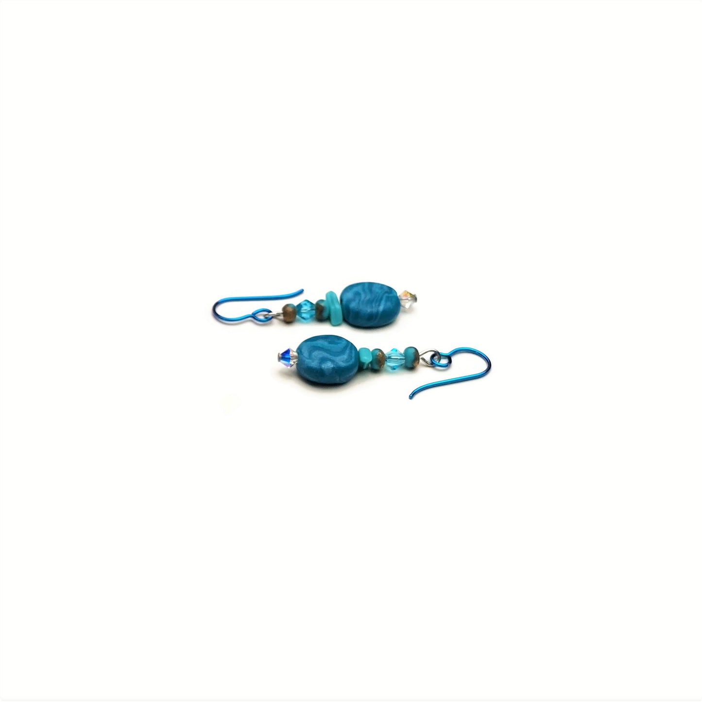 Polymer clay disk bead and crystal drop earrings with teal niobium ear wires on white background